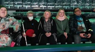 Viisi ihmistä Nokia Arenan katsomossa. Johanna käyttää sähköpyörätuolia, Annamilla on valkoinen keppi.