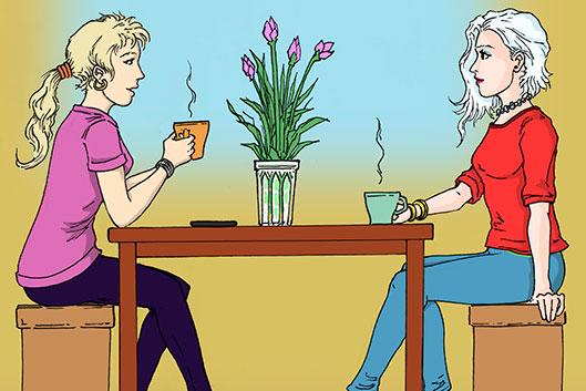 Kaksi nuorta naista istuu pöydän äärellä kahvilassa.