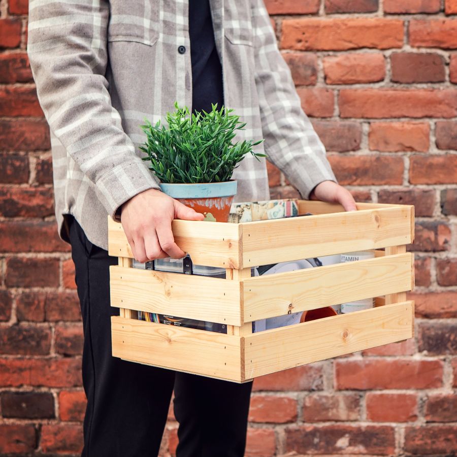 Muuttolaatikkoa kantavat kädet.