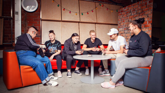 Kuusi nuorta pelaa lautapeliä.