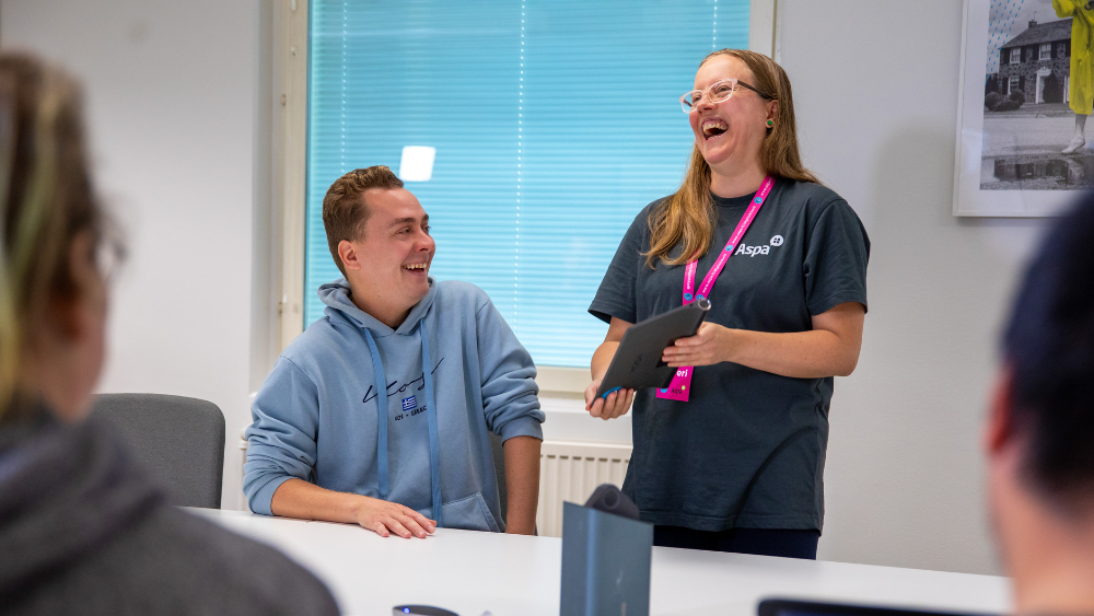 Kaksi hymyilevää ihmistä katsoo pädiä.