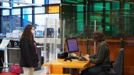 Asiakas ja virkailija kirjastossa.