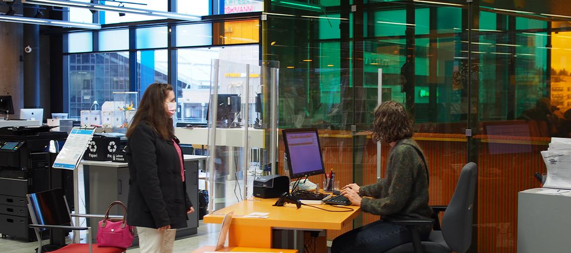 Asiakas ja virkailija kirjastossa.