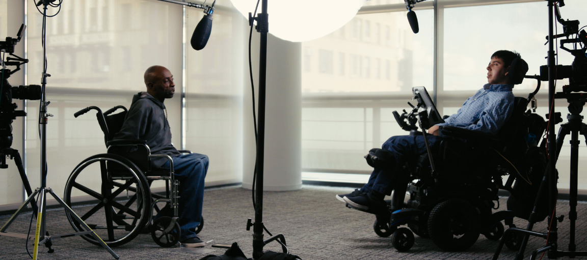 Kaksi pyörätuolissa istuvaa miestä äänistudiossa.