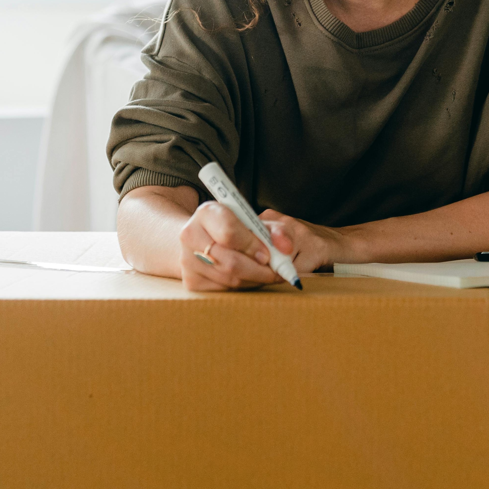 Ihminen kirjoittaa tussilla muuttolaatikkoon.