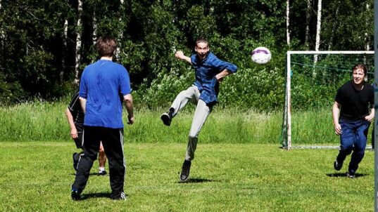 Kolme miestä pelaa jalkapalloa.