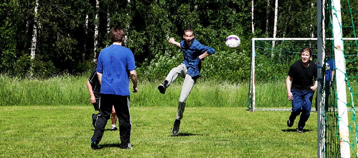 Kolme miestä pelaa jalkapalloa.