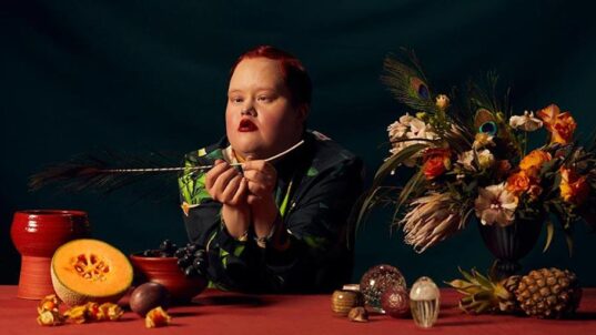 Malli pöydän ääressä, jossa on asetelmia.