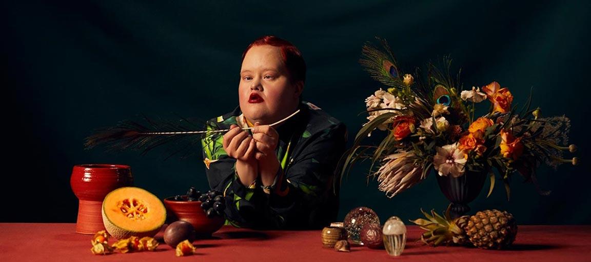 Malli pöydän ääressä, jossa on asetelmia.