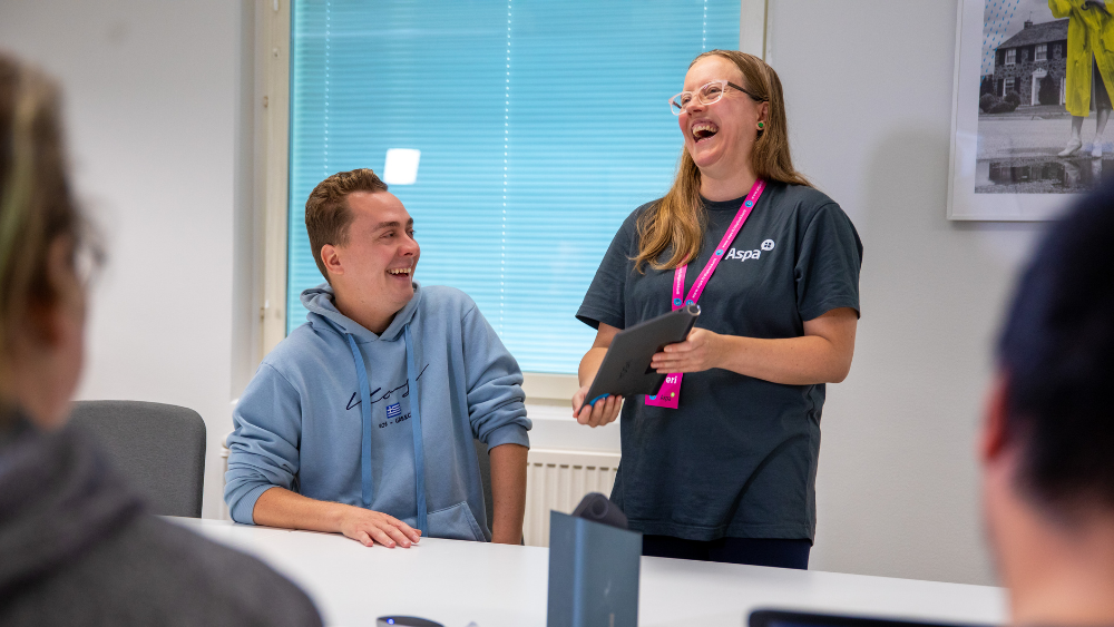 Kaksi hymyilevää ihmistä, jotka katsovat pädiä.