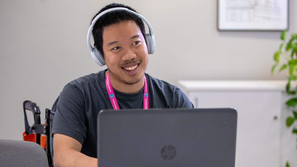 Hymyilevä ihminen tietokoneella.